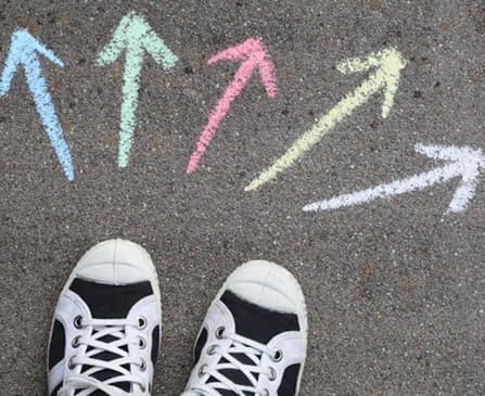 A pair of shoes behind many possible colorful directions drawn on the floor