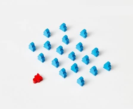 A fallen red piece in front of several standing blue pieces